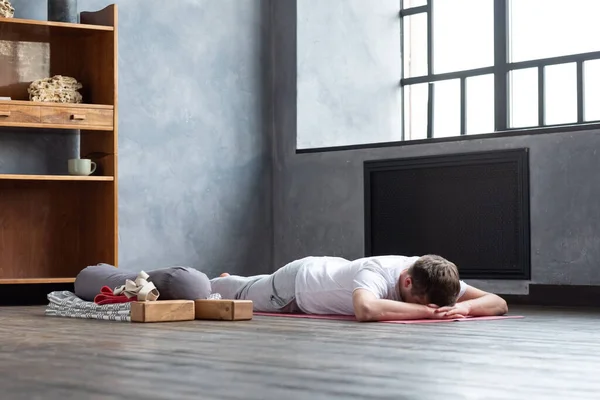 Yoga antrenmanından sonra makarasana 'da yerde dinlenen bir adam.. — Stok fotoğraf