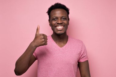 Yakışıklı siyah adam neşeli bir tavırla baş parmağını gösteriyor.