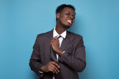 Hüsrana uğramış Afrikalı iş adamı sıkı çalışma gününden sonra kravatı çözüyor..