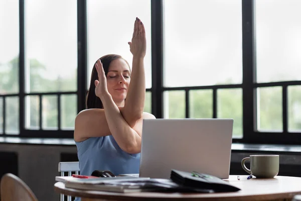 Mulher com seus braços cruzados fazendo exercício de ioga descansando durante o dia de trabalho. — Fotografia de Stock