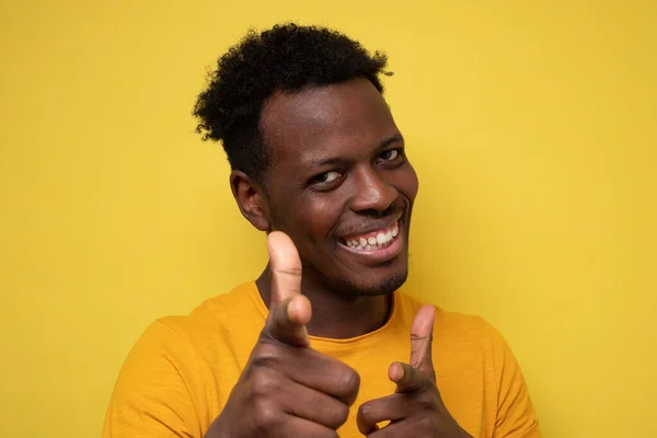 Divertido joven africano sonriendo felizmente y señalando sus dedos índice a la cámara — Foto de Stock