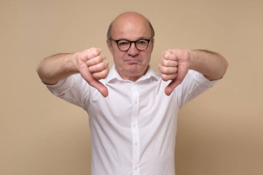 Beyaz tişörtlü yaşlı adam başparmağını kaldırıyor.