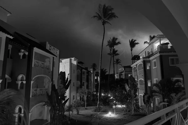 Monocrome long exposure shot of residence in small town Bavaro. Shot made in stormy night with heavy cloudy sky and lightnings in it. Path through te residence is lighten with small lanterns.