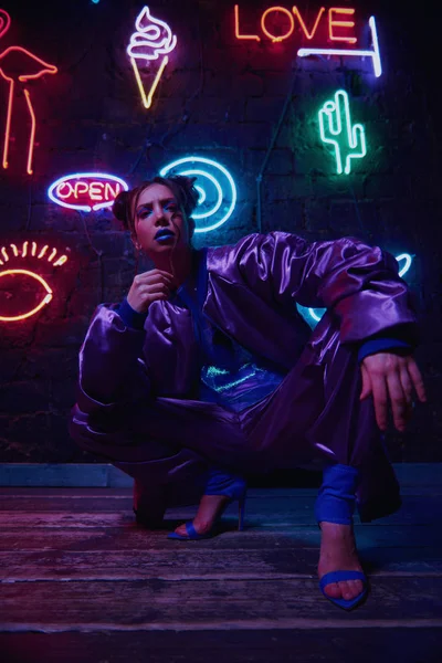 Cyberpunk tiro de modelo vestindo sportswear contemporânea contra a parede de néon — Fotografia de Stock