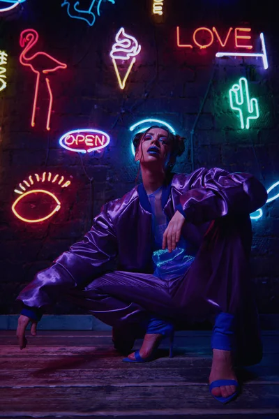 Cyberpunk schieten van model het dragen van hedendaagse sportkleding tegen muur van neon — Stockfoto