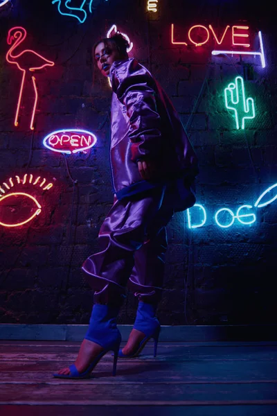 Cyberpunk schieten van model het dragen van hedendaagse sportkleding tegen muur van neon — Stockfoto