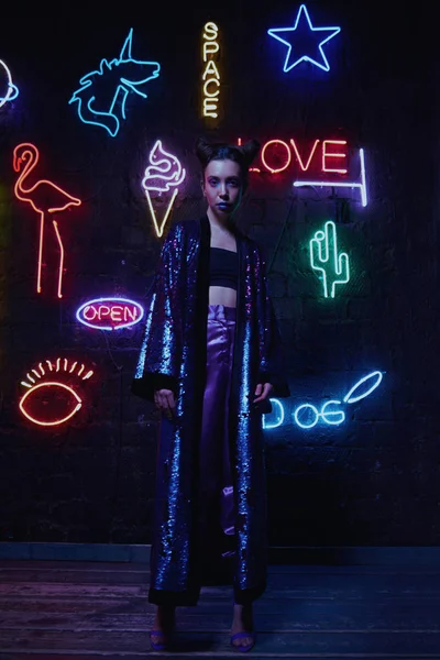 cyberpunk shooting of model wearing bathrobe with glitter against wall of neon