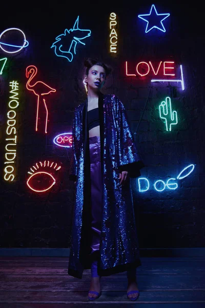 Cyberpunk schieten van model dragen badjas met glitters tegen de muur van neon — Stockfoto