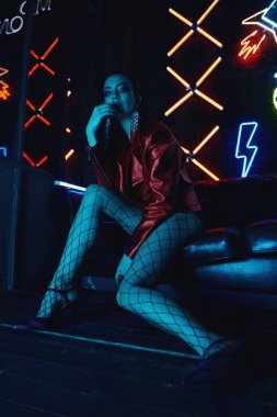 neon karşı deri kanepede oturan kırmızı bisikletçiler ceket giyen model cyberpunk çekim