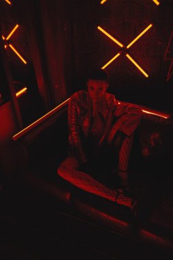 neon karşı deri kanepede oturan kırmızı bisikletçiler ceket giyen model cyberpunk çekim