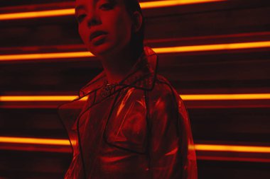 neon duvara karşı selofan ve kırmızı elbise şeffaf kat giyen model cyberpunk çekim