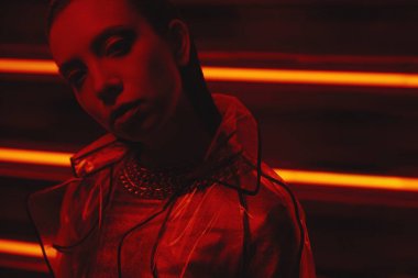 neon duvara karşı selofan ve kırmızı elbise şeffaf kat giyen model cyberpunk çekim