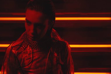 neon duvara karşı selofan ve kırmızı elbise şeffaf kat giyen model cyberpunk çekim