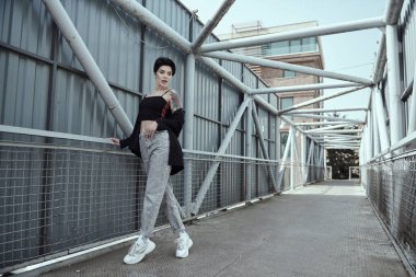 Köprüde poz veren dövmeli kuzgun saçlı genç bayan