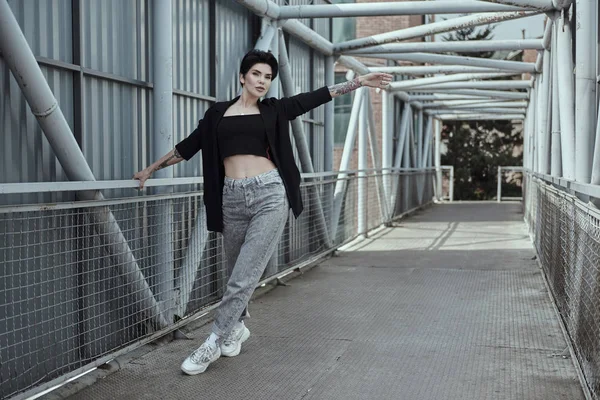 Corbeau jeune femme aux cheveux tatoués posant sur le pont — Photo