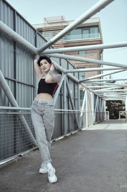 Köprüde poz veren dövmeli kuzgun saçlı genç bayan