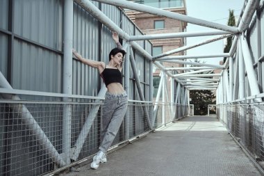 Köprüde poz veren dövmeli kuzgun saçlı genç bayan