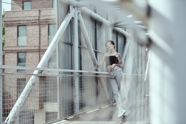 Köprüde poz veren dövmeli kuzgun saçlı genç bayan