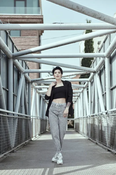 Raven haired young lady with tattoos posing on the bridge — Stock Photo, Image