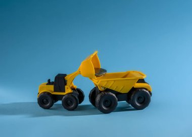 Yükleme sarı oyuncak buldozer sarı oyuncak kamyon para paralar. Metin için yer. Mavi arka plan