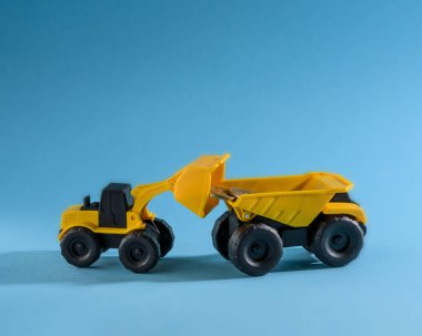 Yükleme sarı oyuncak buldozer sarı oyuncak kamyon para paralar. Metin için yer. Mavi arka plan
