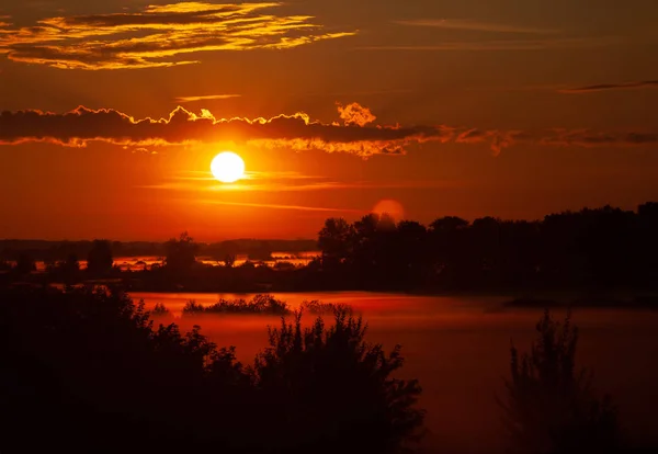 Red sunrise and morning fog at the field