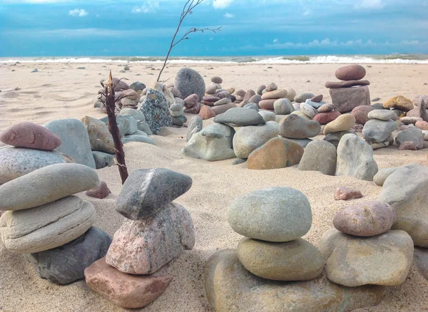 Tower and labyrinth of stones on sea beach background. Zen, stones, sand, sea.