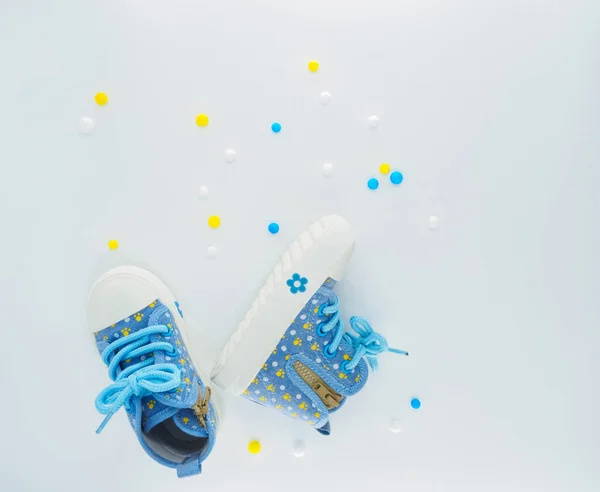 Flat lay with blue childrens  sneakers with blue and yellow balls at white background