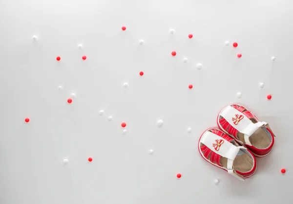 Flat lay of pair of white red sandals with clasps fasteners and with white and red balls at white background