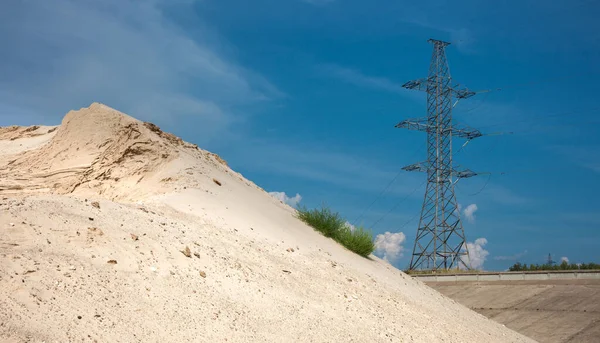 Heaps of sand washed up from the river. High-voltage power line at background