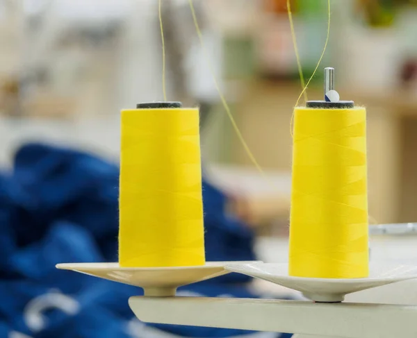 Rolls of yellow cotton thread for sewing with overlock machine.