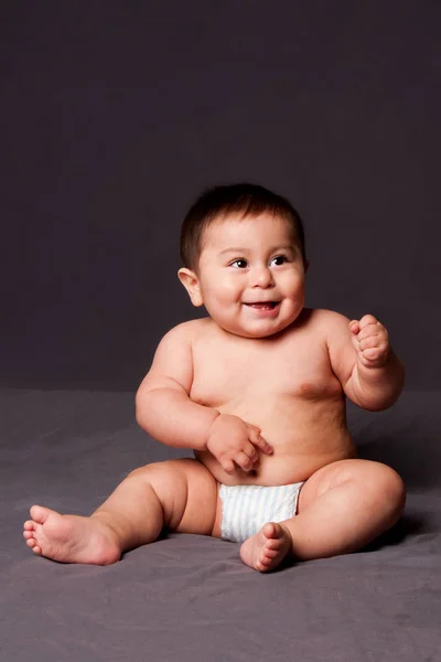 可爱的快乐有趣的微笑的婴儿坐在 而穿着尿布 在灰色 — 图库照片