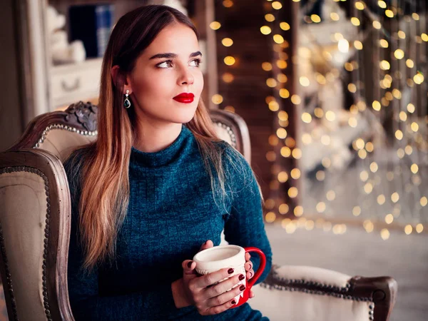 Улыбающаяся красивая женщина сидит дома возле рождественской елки — стоковое фото