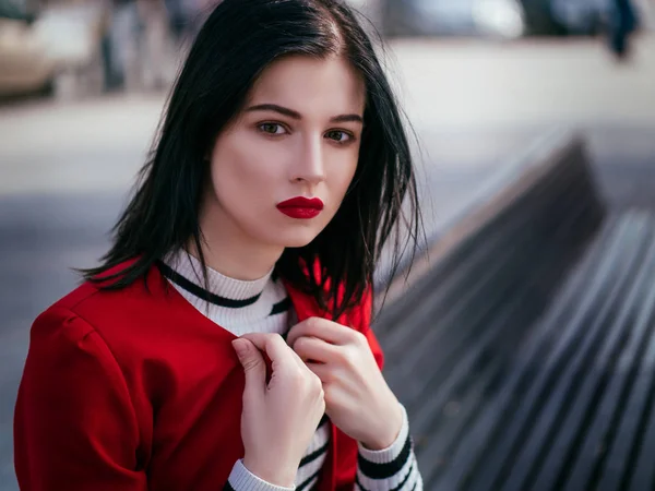 Schönes glamouröses brünettes Mädchen in roter Jacke posiert — Stockfoto