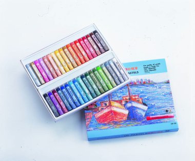 Renkli pastel kalemler beyaz arkaplanda bir kutuda