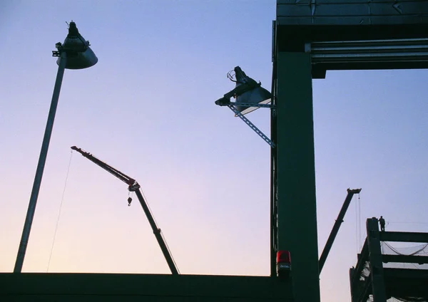 日没の空の背景の建設側のライターとクレーン — ストック写真