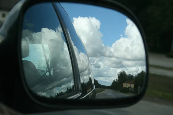 阳光明媚的夏日天空中有云彩和树木反射在汽车侧面镜子作为旅行背景 — 图库照片
