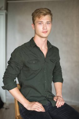 Bir çekim Genç beyaz yakışıklı sarışın adamın gri bir arka plana dayanır.