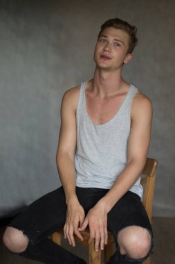 Bir çekim Genç beyaz yakışıklı sarışın adamın gri bir arka plana dayanır.