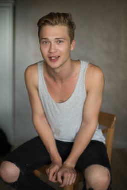 Bir çekim Genç beyaz yakışıklı sarışın adamın gri bir arka plana dayanır.