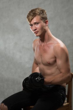 Bir çekim Genç beyaz yakışıklı sarışın adamın gri bir arka plana dayanır.