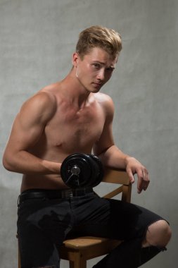 Bir çekim Genç beyaz yakışıklı sarışın adamın gri bir arka plana dayanır.