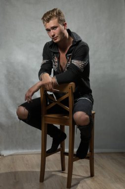 Bir çekim Genç beyaz yakışıklı sarışın adamın gri bir arka plana dayanır.