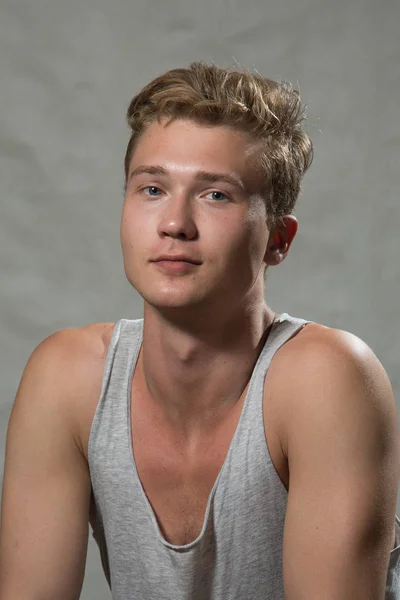 A shoot of young caucasian handsome blonde man against grey background.