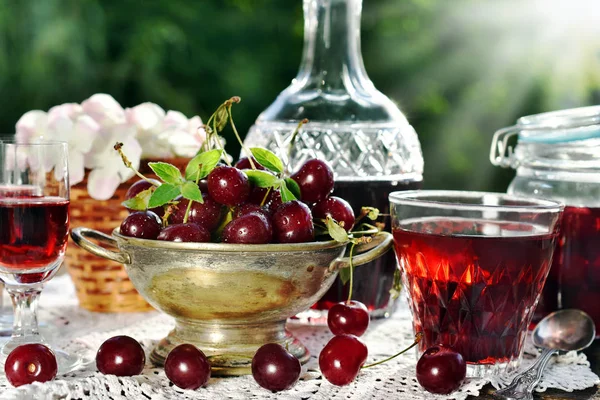 复古风格仍然生活与自制樱桃甜酒在水晶水瓶和新鲜水果在花园的桌子上 — 图库照片