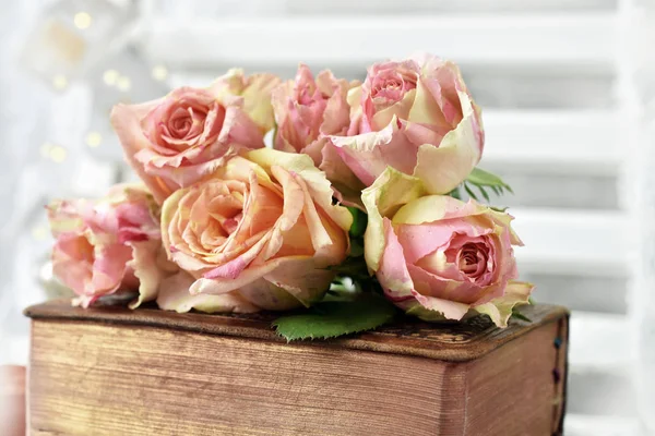 bunch of beautiful multicolor roses lying on old book