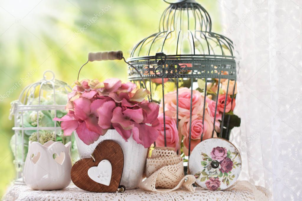 vintage style decoration with flowers,bird cages and laces on the table in the garden 