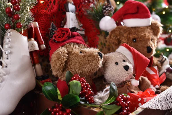 three vintage style teddy bears in santa caps sitting in old suitcase in front of christmas tree