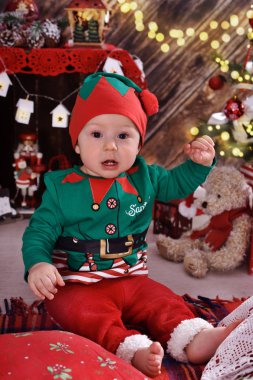 küçük çocuk (10 gün) ilk odada Noel ağacı ve enjoing önünde oturuyor Noel