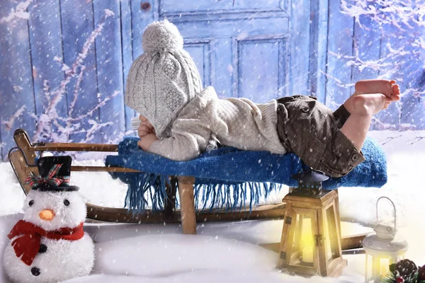 冬天的风景与可爱的小男孩躺在他的肚子上雪橇 — 图库照片